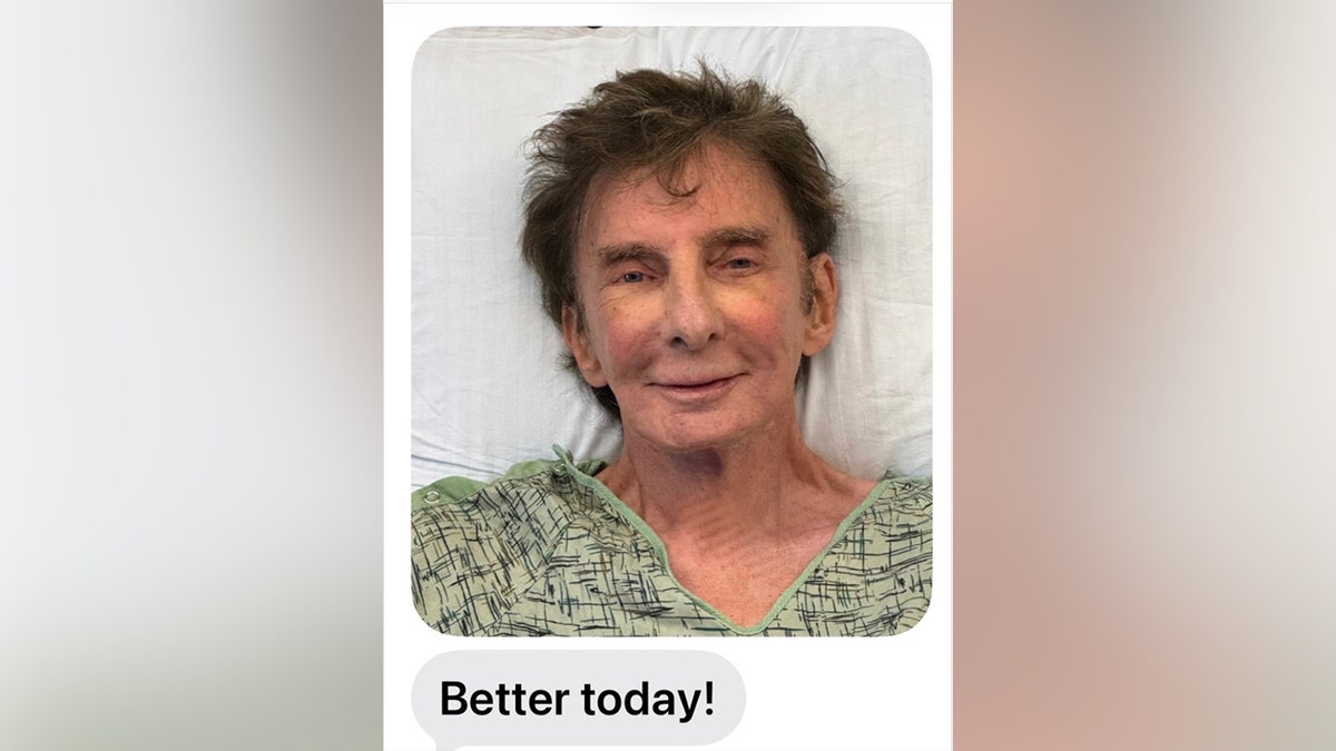 Barry Manilow smiling while in a hospital gown.