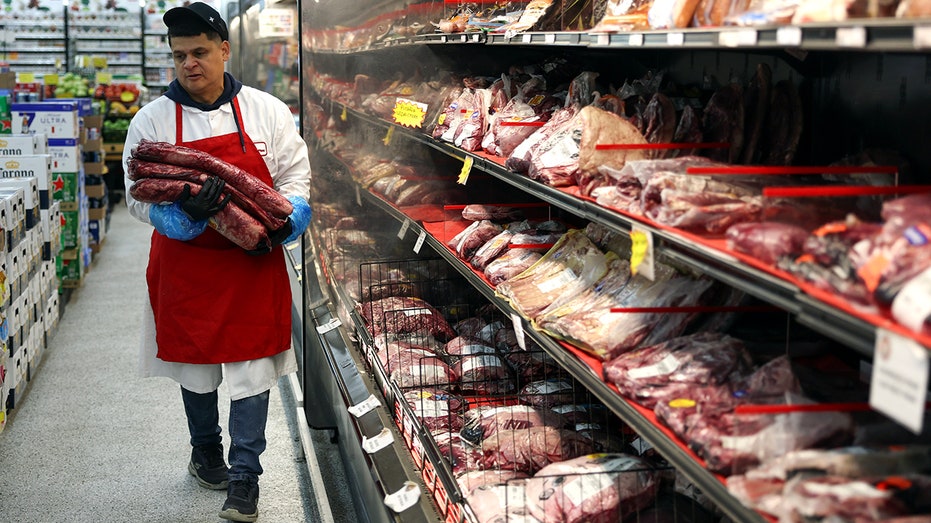 Marlo Ramirez carries slabs of beef to be prepared for a customer in a grocery store on July 2