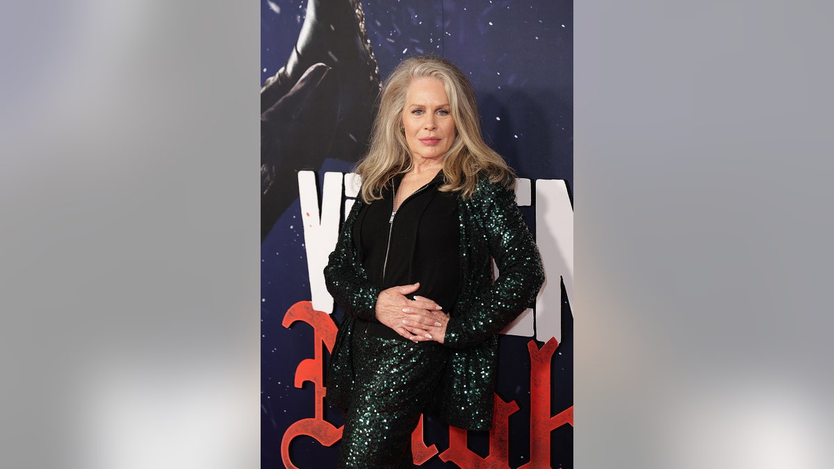 Beverly D'Angelo wearing a sparkly black suit posing for the camera.