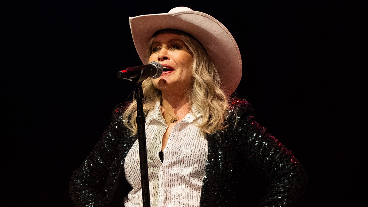 Beverly D'Angelo singing on stage with a pink cowboy hat.