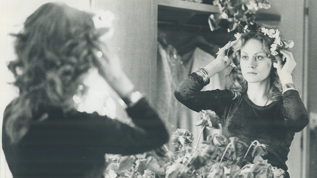 A young Beverly D'Angelo looking at herself in the mirror.