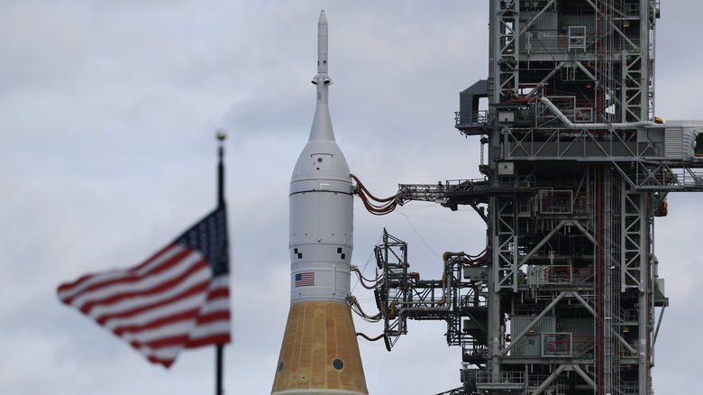 NASA's Artemis II rocket at the Kennedy Space Center with an American flag waving over it