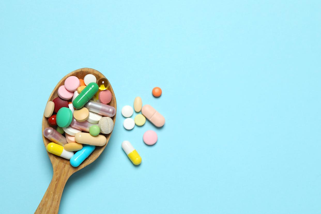 a wooden spoon holding an array of colorful supplement pills