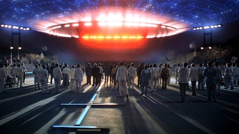 A large gathering of people greet the landing spacecraft in 