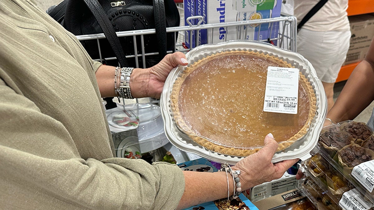 A woman holds a Kirkland Signature's giant pumpkin pie at Costco.