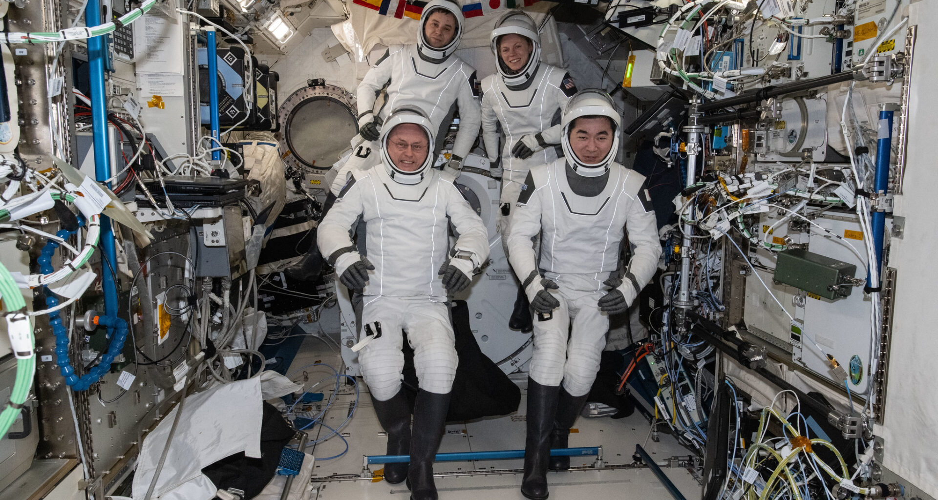 Four SpaceX Crew-11 members gather together for a crew portrait wearing their Dragon pressure suits during a suit verification check inside the International Space Station's Kibo laboratory module.