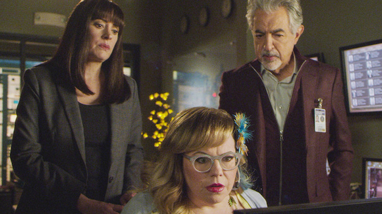 Emily Prentiss standing next to David Rossi, with Penelope Garcia sitting