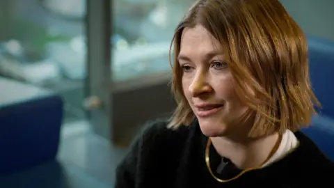 BBC News Nicki, who has a cropped bob hairstyle, looks to the side of the camera while chatting with the BBC