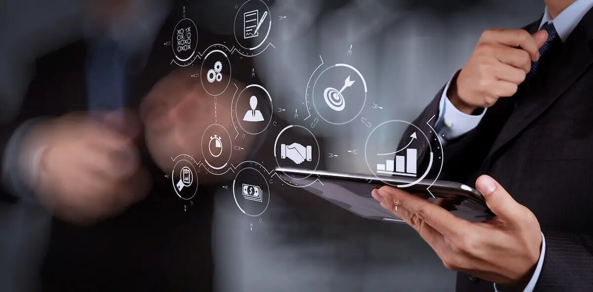 close up of businessman holding a tablet with digital process icons overlaid on the image