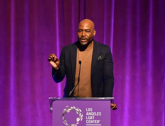 Karamo Brown speaks at a podium with Los Angeles LGBT Center signage in the background