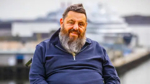 Supplied A man with a long grey bread and spiky hair wearing a navy pullover.