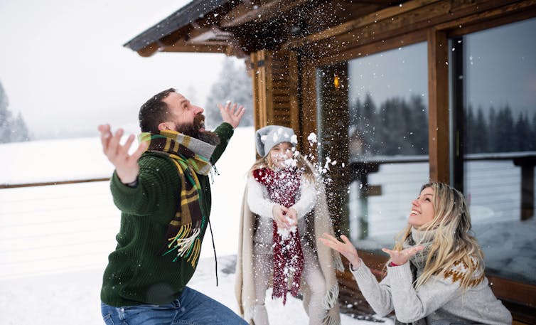 A family of three is outdoors enjoying the snow.