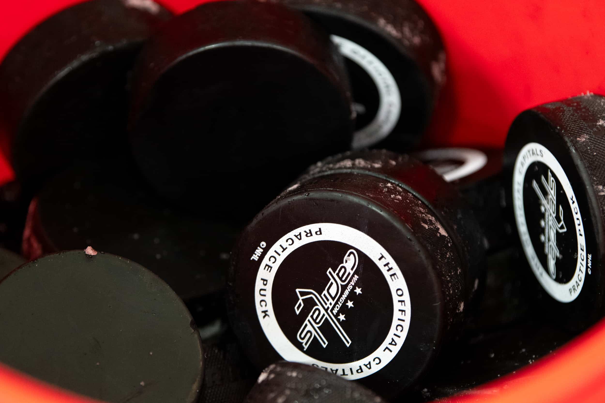 Inside of a red bucket full of Capitals practice pucks