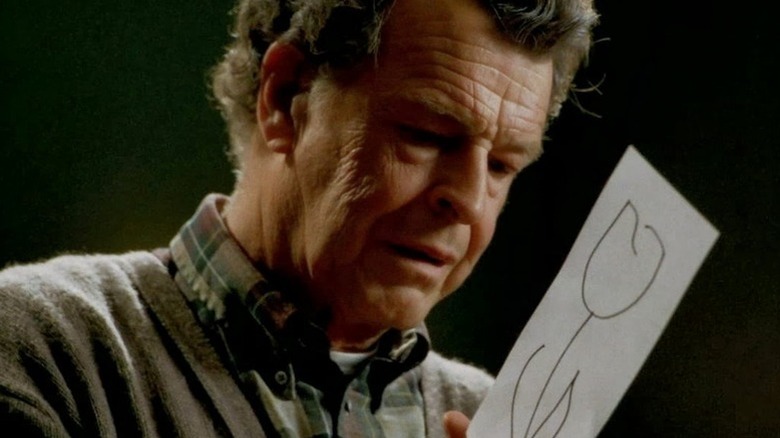 A visibly shaken Walter Bishop (John Noble) holds a drawing of a flower in Fringe