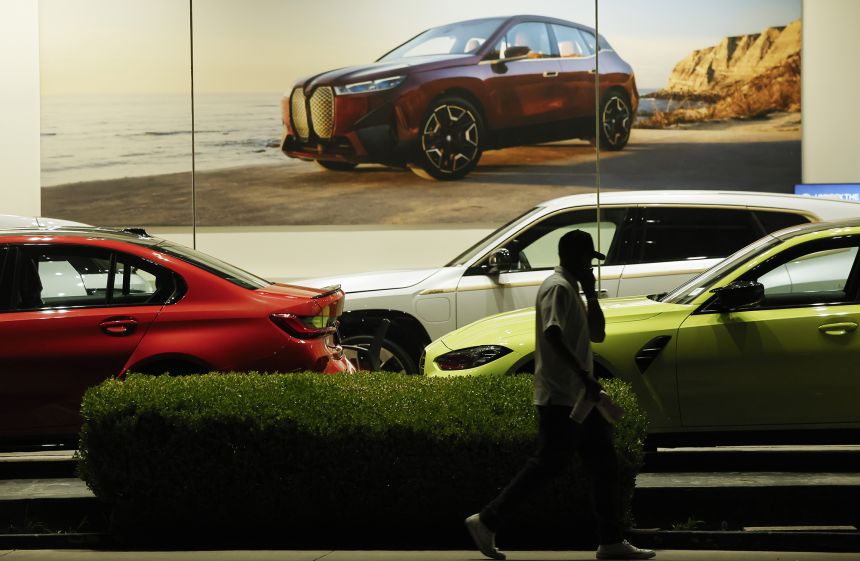 A person walks past BMW cars displayed for sale at a dealership on April 7, 2025 in Glendale, California.