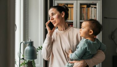 A woman holding a baby while on the phone.
