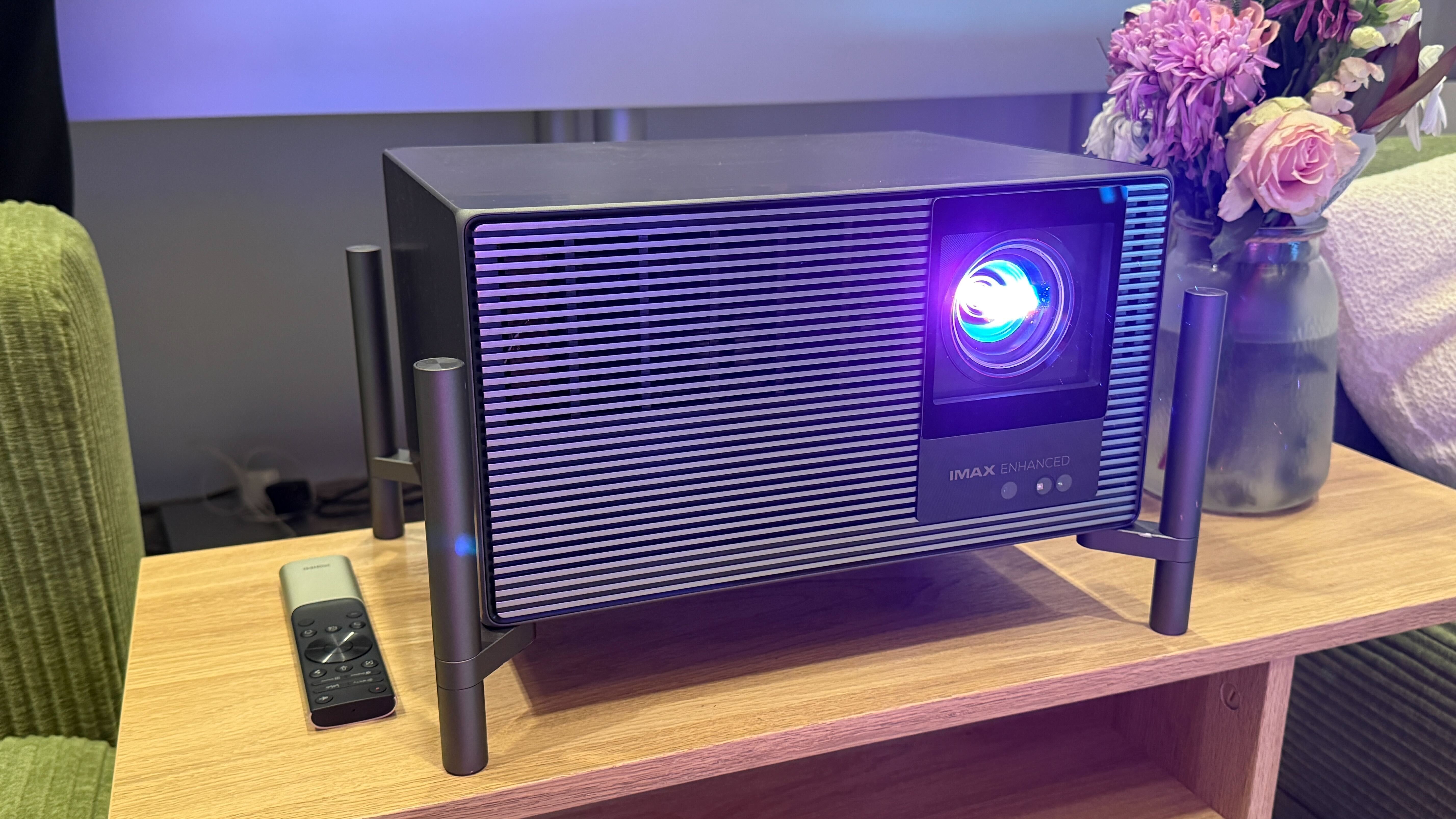 An Xgimi projector on a wooden table with a light beaming from its lens