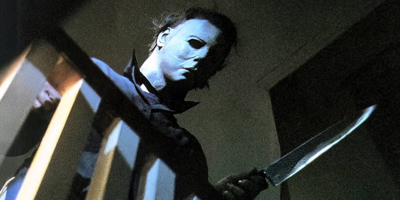 Michael Myers, looking down from the stairs balcony, holding a knife in Halloween (1978).