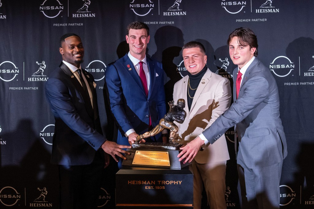 Heisman Trophy finalists (L-R) Notre Dame running back Jeremiah Love, Indiana quarterback Fernando Mendoza, Vanderbilt quarterback Diego Pavia and Ohio State quarterback Julian Sayin pose with the trophy after attending an NCAA college football news conference before the award ceremony on December 13, 2025, in New York.  