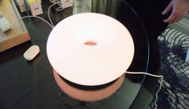 Ikea's glowing smart lamp and various devices on a table.