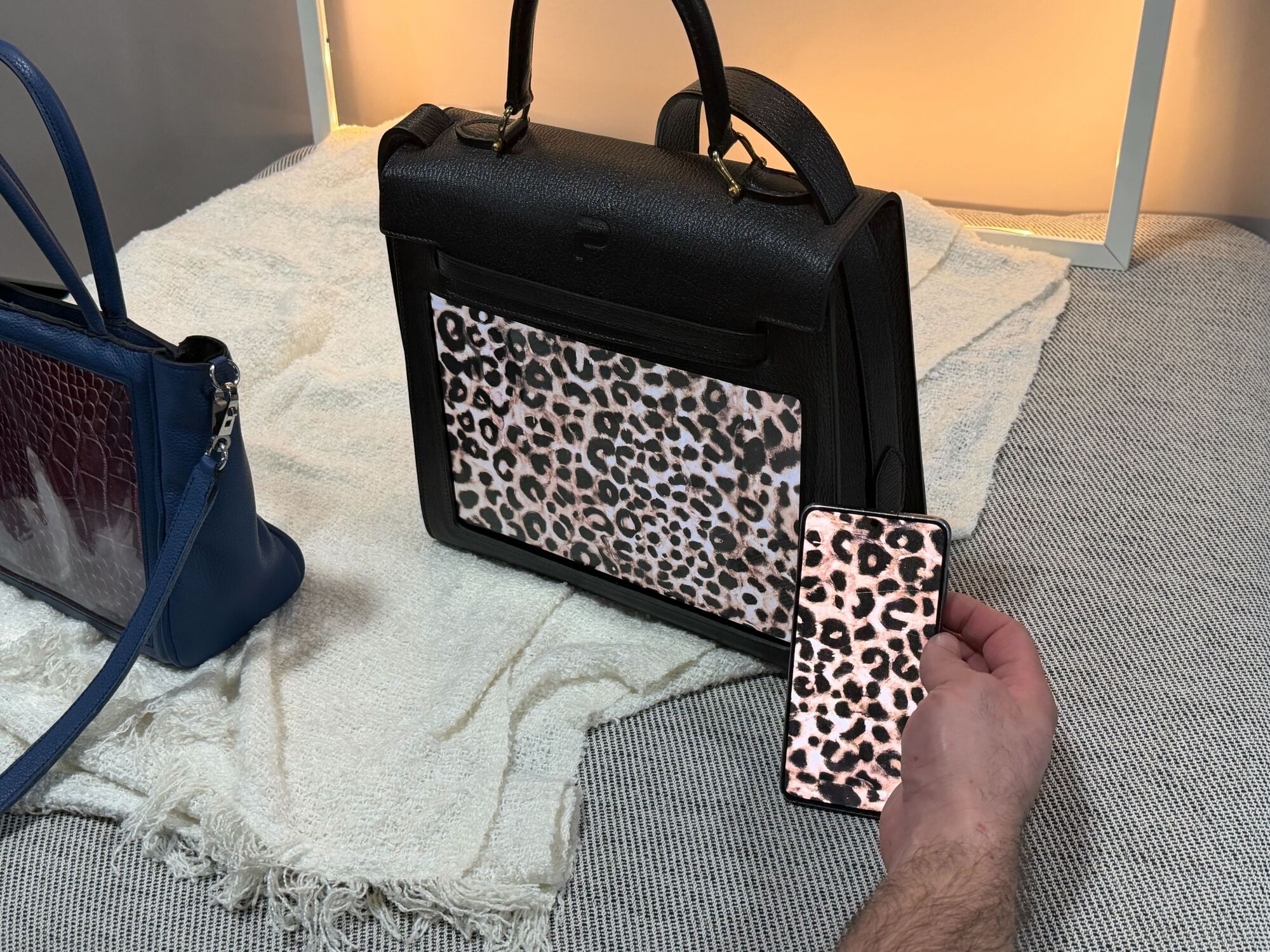 Man holding a phone with cheetah print next to handbag with the same design