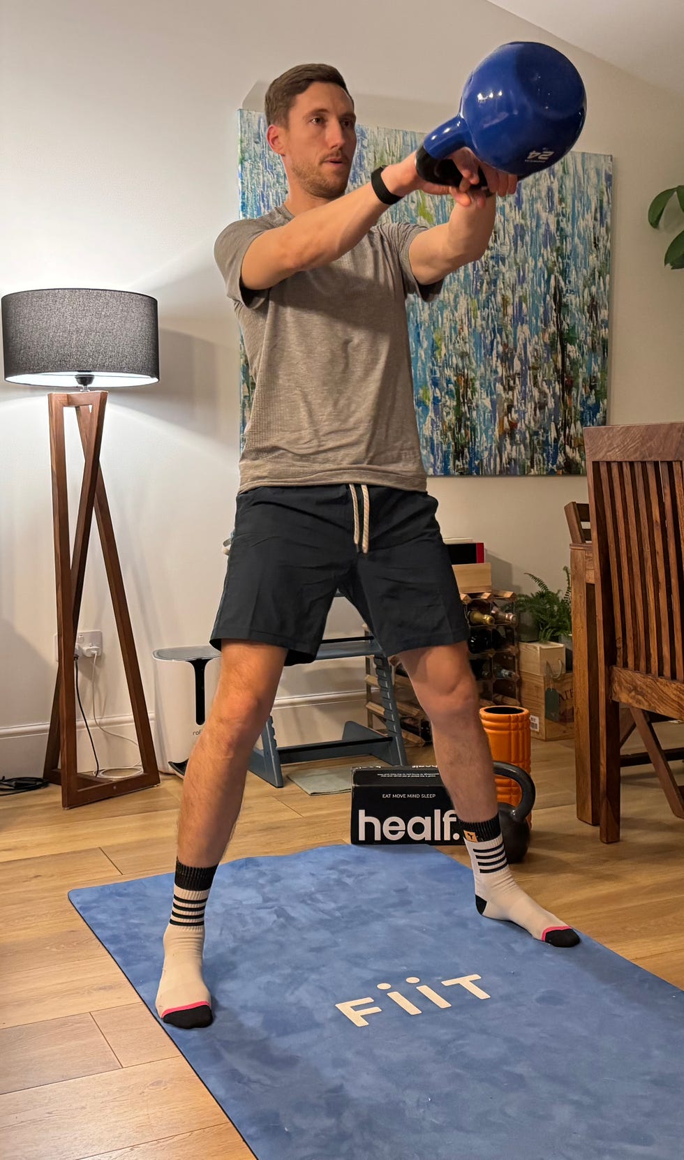 individual exercising with a kettlebell on a workout mat in a home setting
