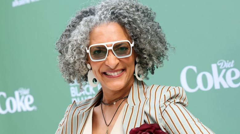 Carla Hall in white rimmed glasses and striped jacket