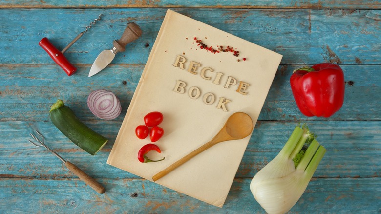 Recipe book on table with kitchen utensils and vegetables