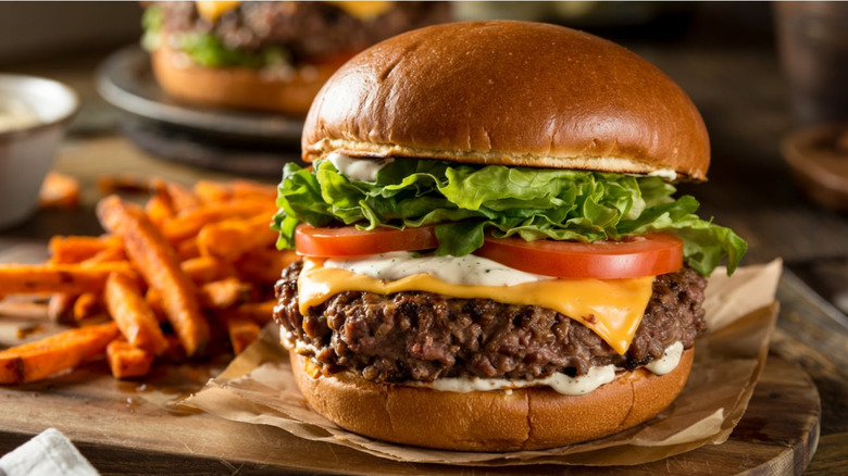 Thick bison burger next to sweet potato fries