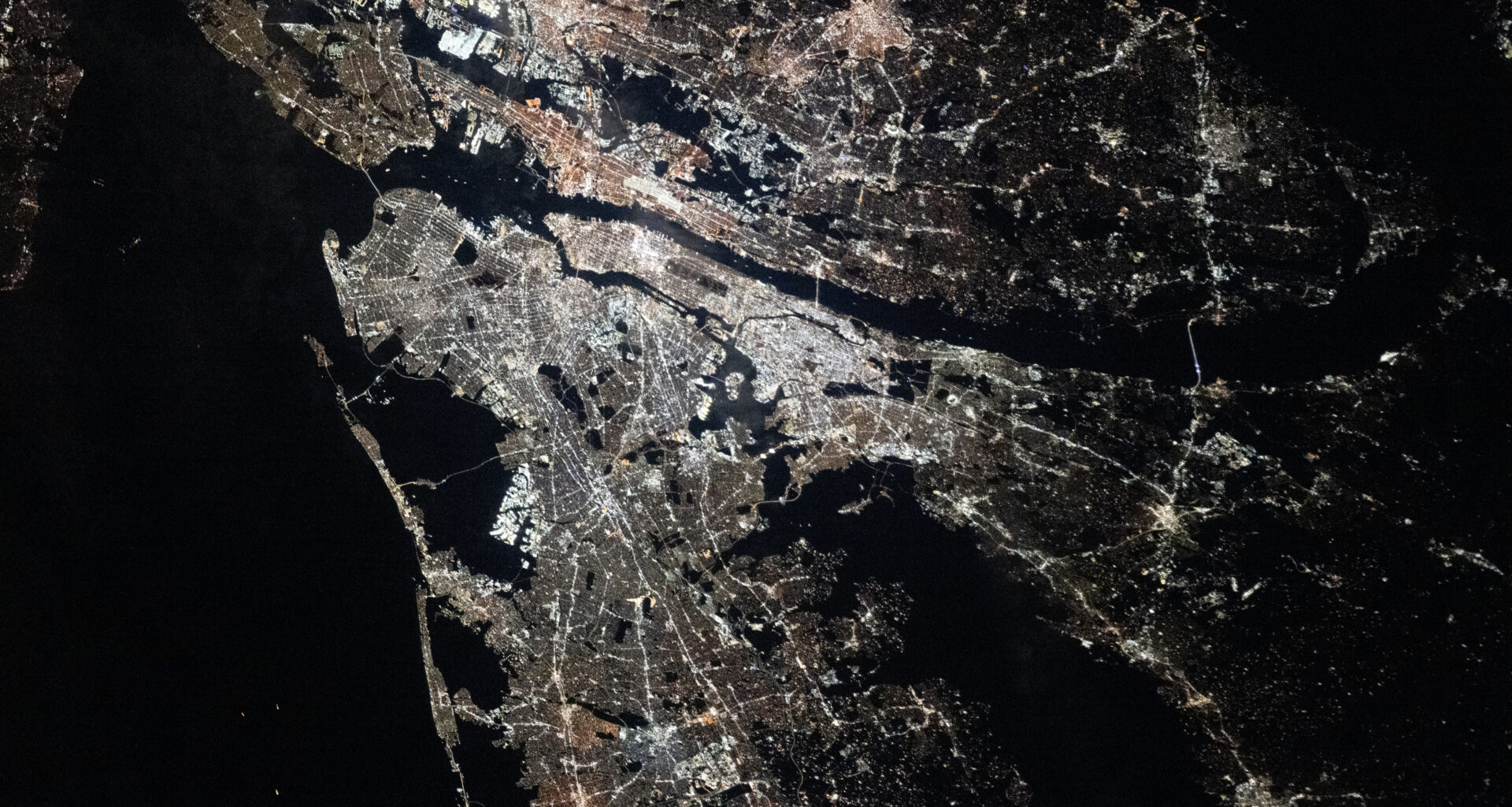The New York–Newark–Jersey City Metropolitan Area at night. City lights illuminate most of the image.