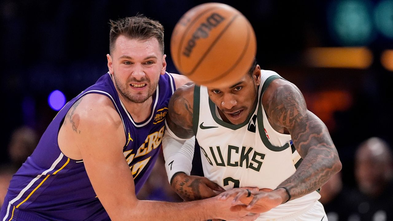 Los Angeles Lakers guard Luka Doncic, left, and Milwaukee Bucks guard Kevin Porter Jr. go after a loose ball during the first half of an NBA basketball game Friday, Jan. 9, 2026, in Los Angeles. (AP Photo/Mark J. Terrill)