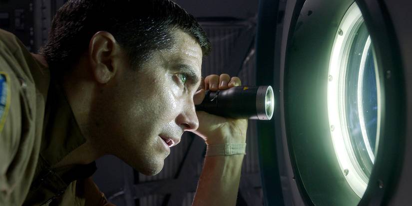 Jake Gyllenhaal shines a flashlight out a portal window in Life.