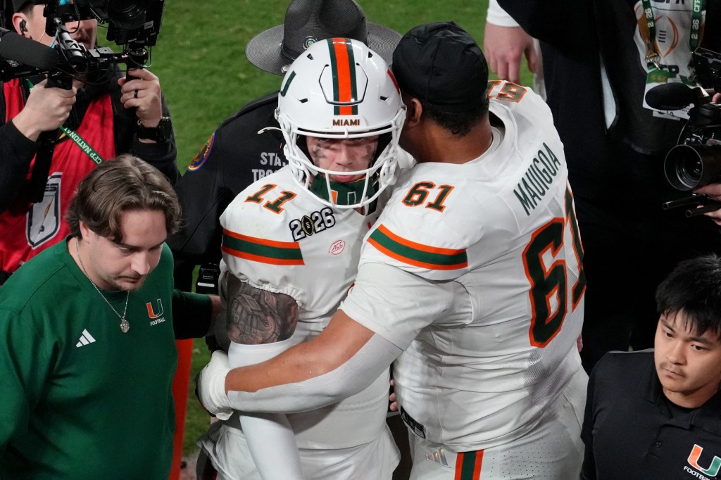 Miami Hurricanes players Francis Mauigoa and Carson Beck hug after losing the CFP National Championship.