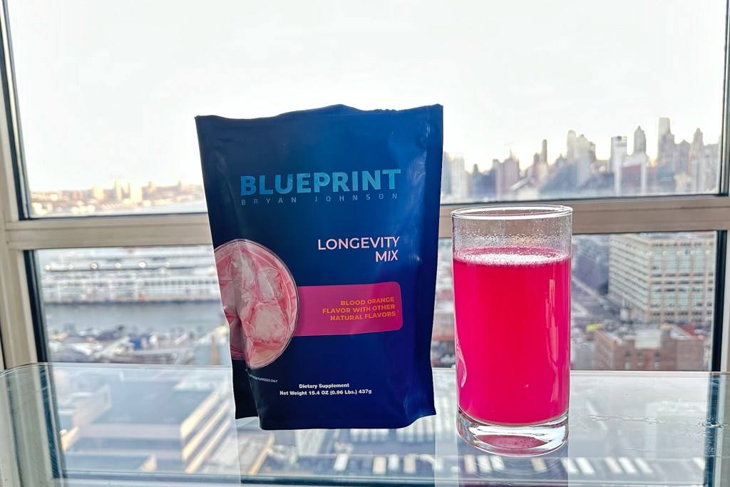 A bag of liquid next to a glass of pink liquid