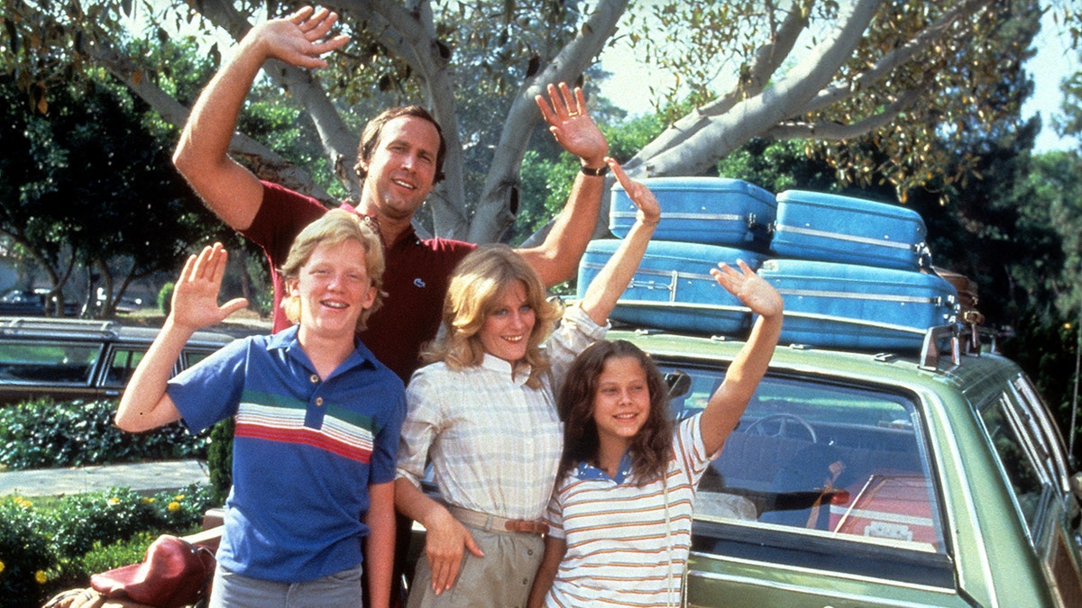 The cast of "National Lampoon" waving from a car.