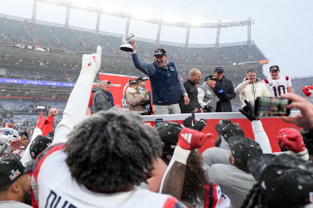 New England Patriots coach Mike Vrabel holds the AFC Championship trophy after a game in snowy Denver.