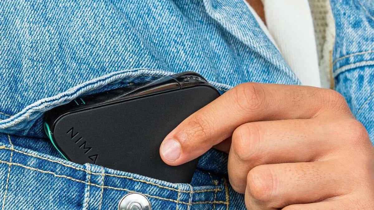 The NIMA Gluten Sensor being put in a denim jacket pocket.