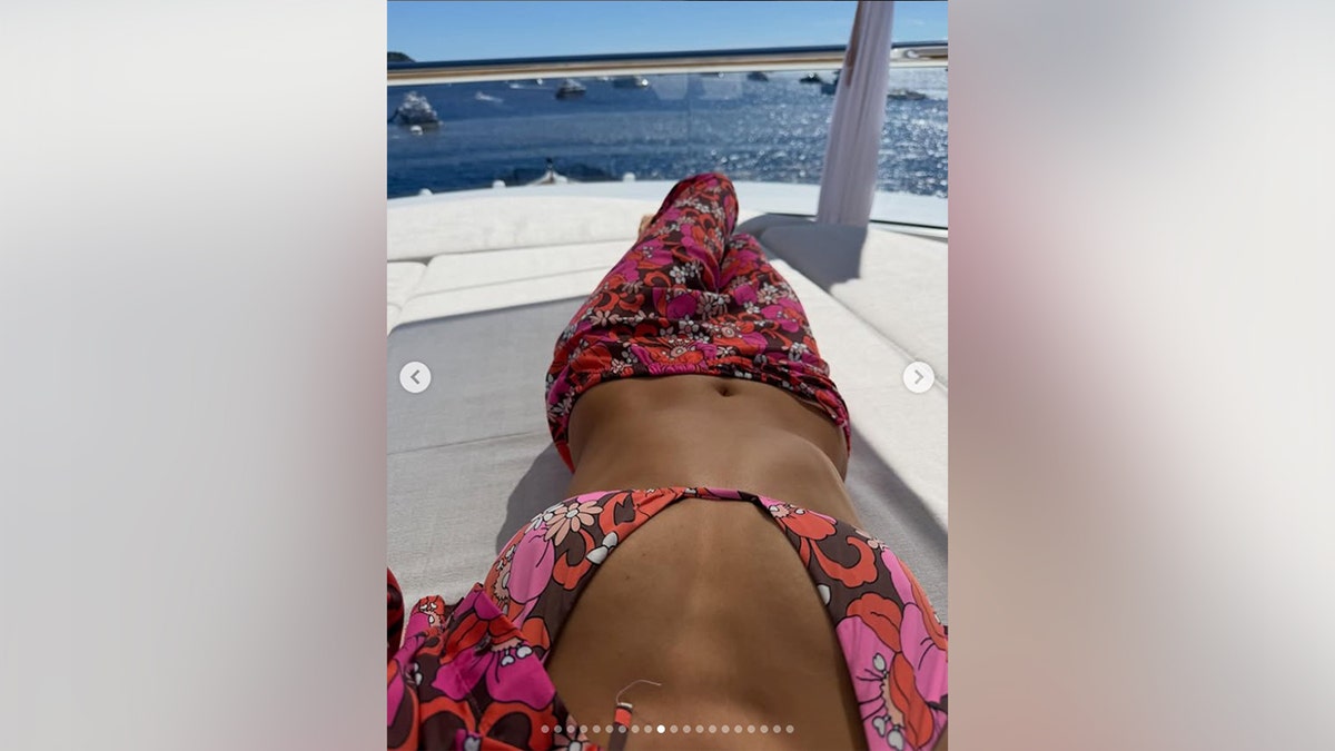 Nina Dobrev showing off her abs in a brown bikini with floral designs.