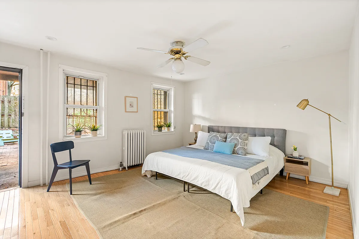 garden level bedroom with ceiling fan, two windows and a door to the rear yard