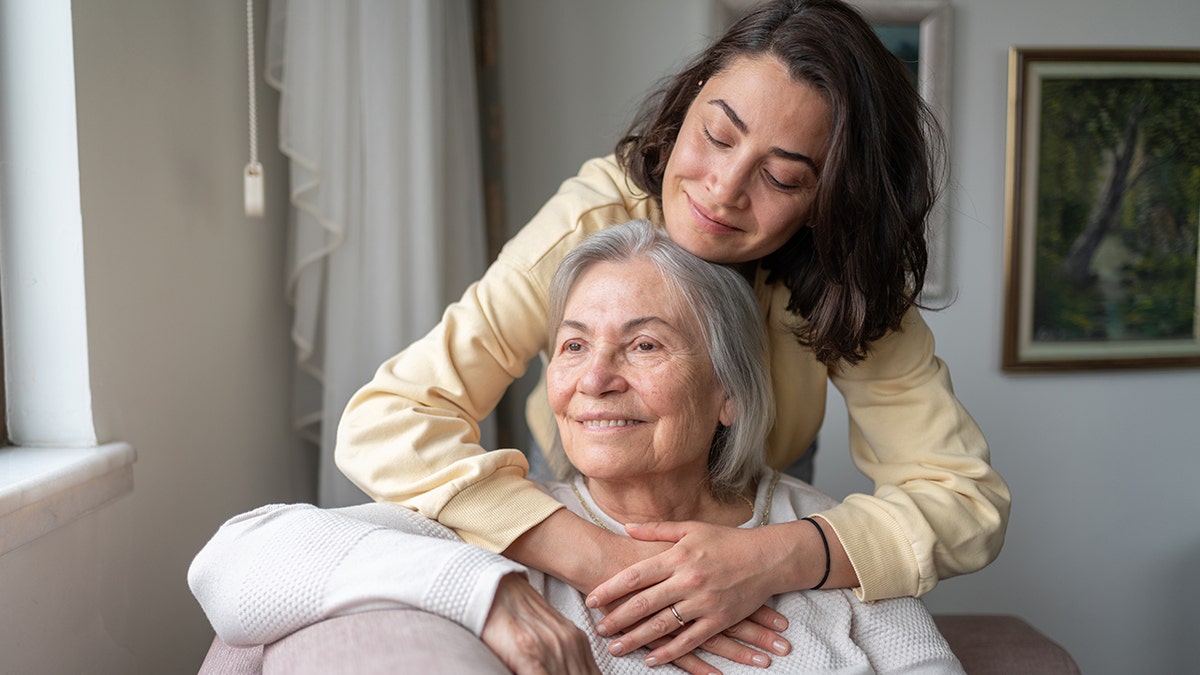 Woman hugging older woman, may have Parkinson's disease