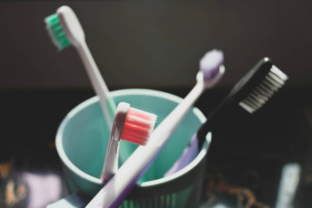 1. Assorted colorful toothbrushes in a teal cup for oral hygiene.