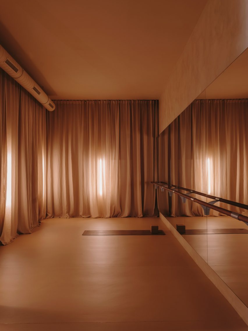 Barre studio with floor-to-ceiling curtains and mirrored walls