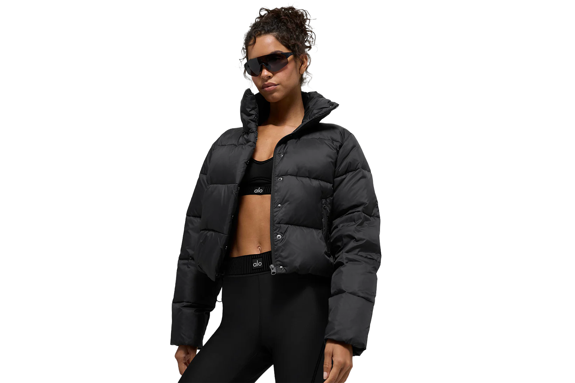 A woman in black activewear with black puffer jacket, black leggings, and black bra.