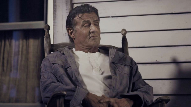 Sylvester Stallone's John Rambo sits in a chair with his eyes closed in Rambo Last Blood
