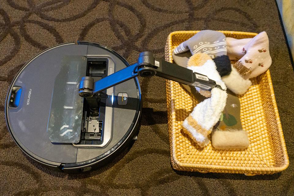The Roborock Saros Z70 uses its robotic arm to put a handful of socks into a basket. 