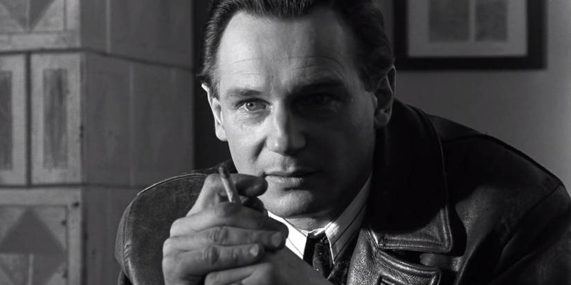 Oskar Schindler looking intently ahead while smoking a cigarrette in Schindler's List