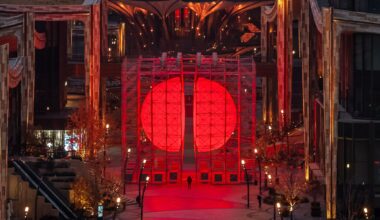 A large-scale installation by SpY of two glowing, red half-spheres within a metal framework