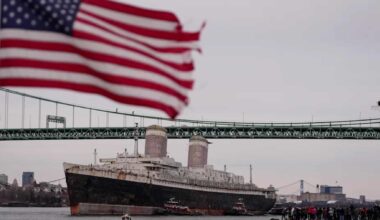 The ocean liner SS United States passes beneath a Delaware River bridge as it departs for conversion into a Gulf artificial reef.