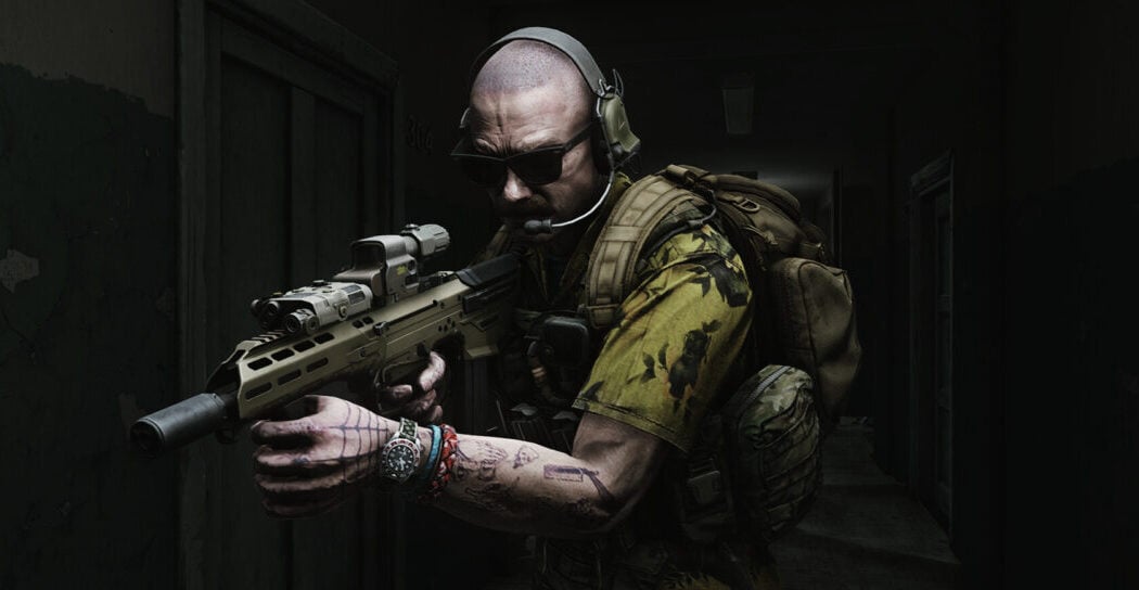 A man carries a rifle down a dark hallway.