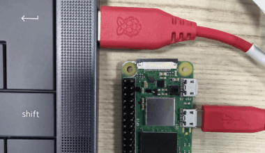 The edge of a laptop is shown with a USB cable plugged into it. the other end of the cable is plugged into a Raspberry Pi Zero.